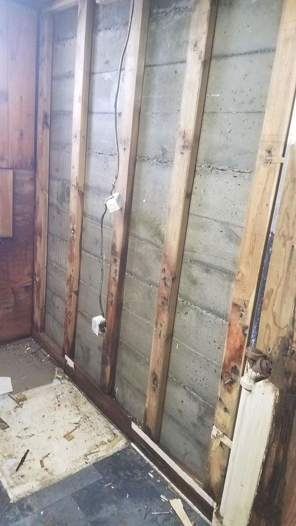 Exposed wall framing with insulation and drywall removed in a room under renovation