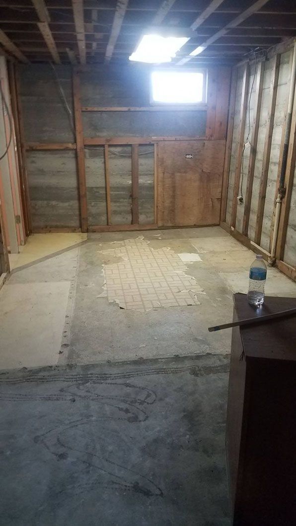 Empty unfinished room with exposed studs, a small window, and a concrete floor.