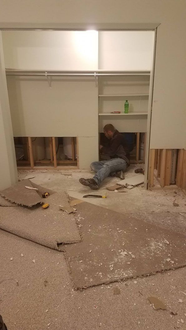 Person lying amid drywall debris in a damaged room with an open closet.
