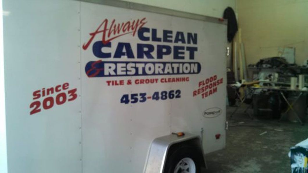 White carpet cleaning trailer with “Always Clean Carpet Restoration” signage in a garage, beside equipment.