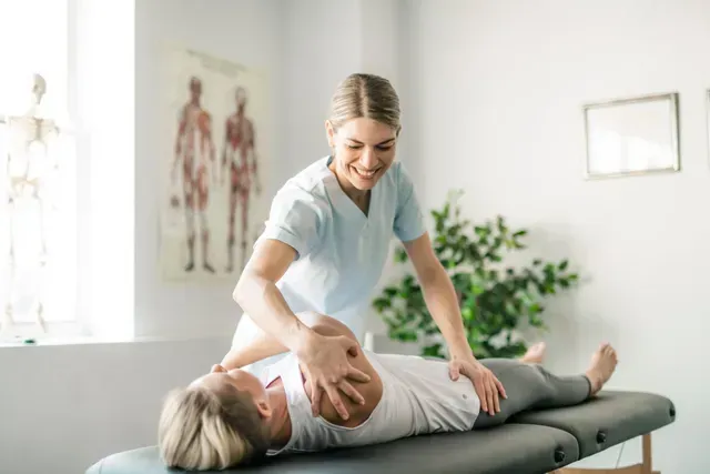 Une femme est allongée sur une table et se fait masser par une infirmière.