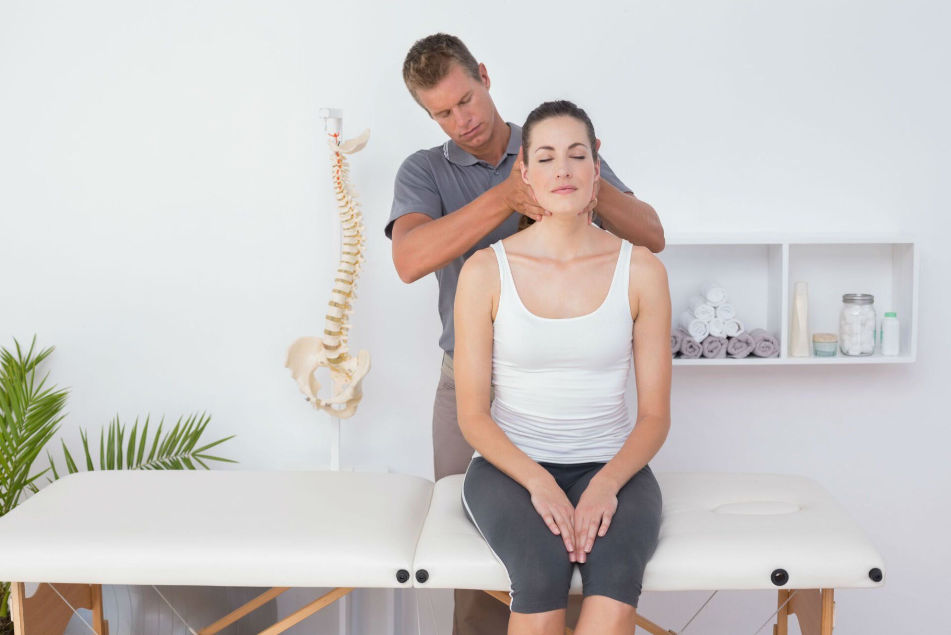 Une femme est assise sur une table et se fait masser le cou par un homme.