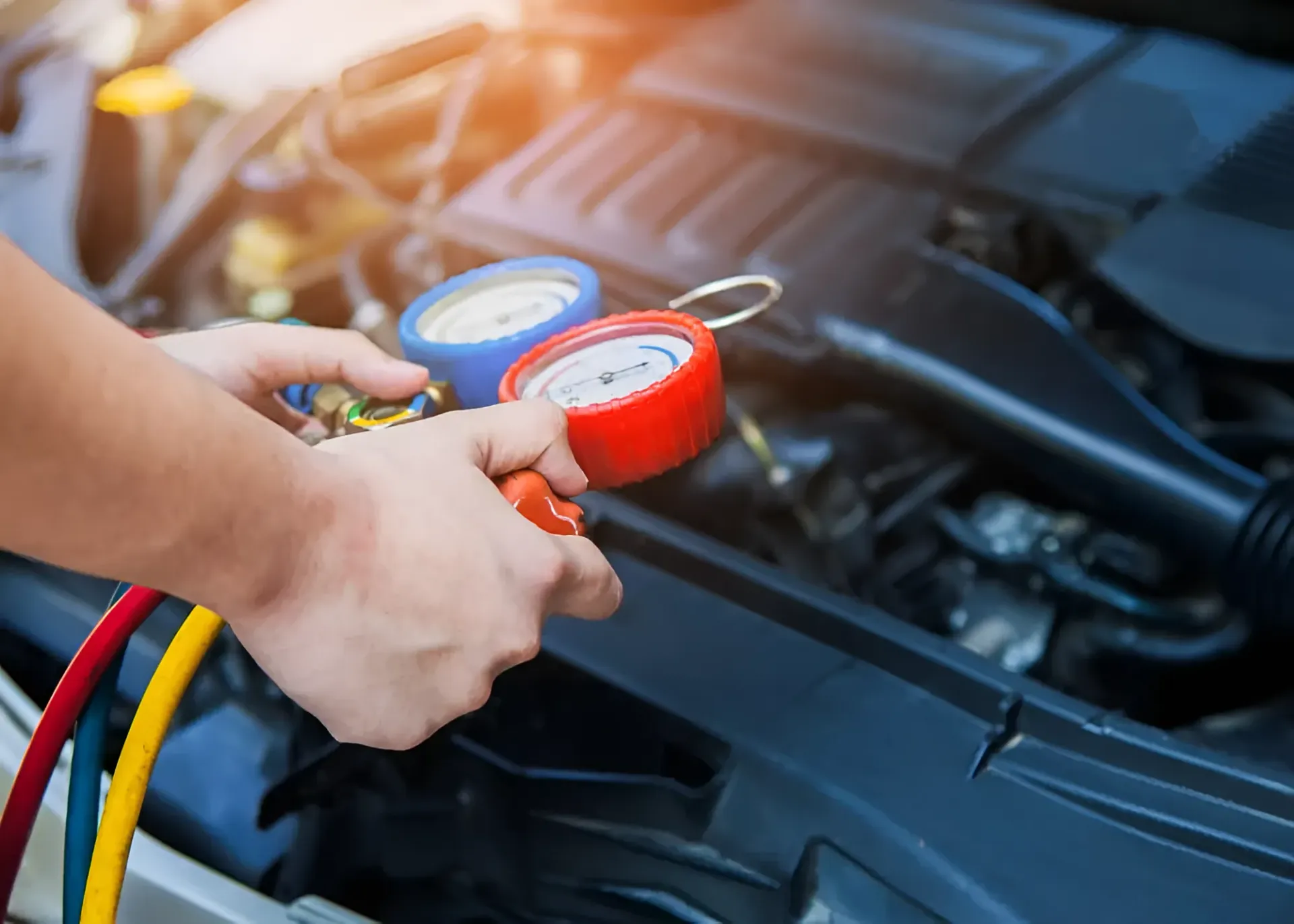 Hands Holding Gauges Over a Car Engine — BJM Mechanical Mufflers & Tyres in Oxenford, QLD