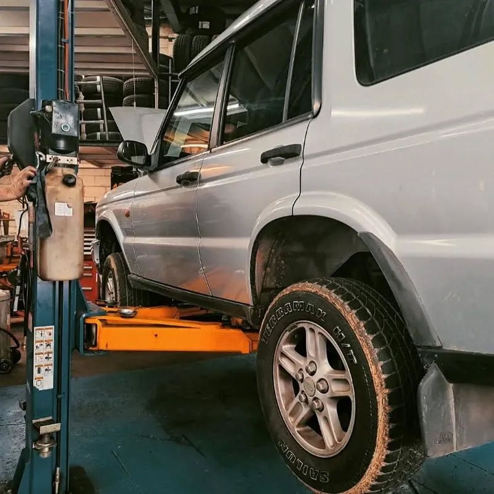 Silver SUV On An Orange Car Lift In A Garage