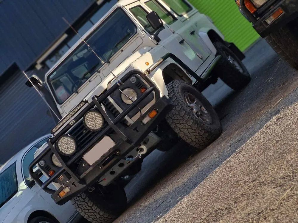 White Land Rover Defender Parked On A Paved Lot
