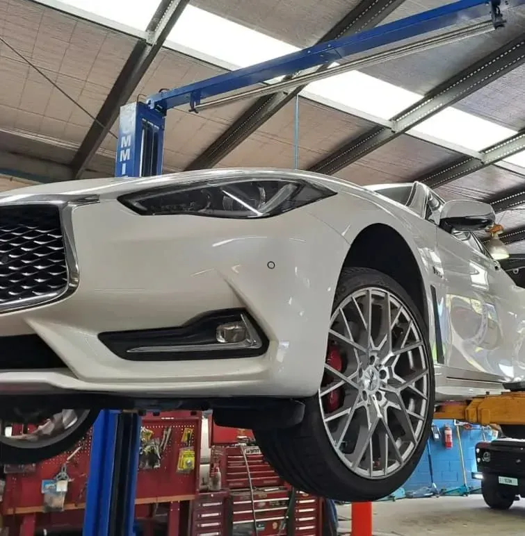 White Sports Car on a Lift in a Garage — BJM Mechanical Mufflers & Tyres in Oxenford, QLD