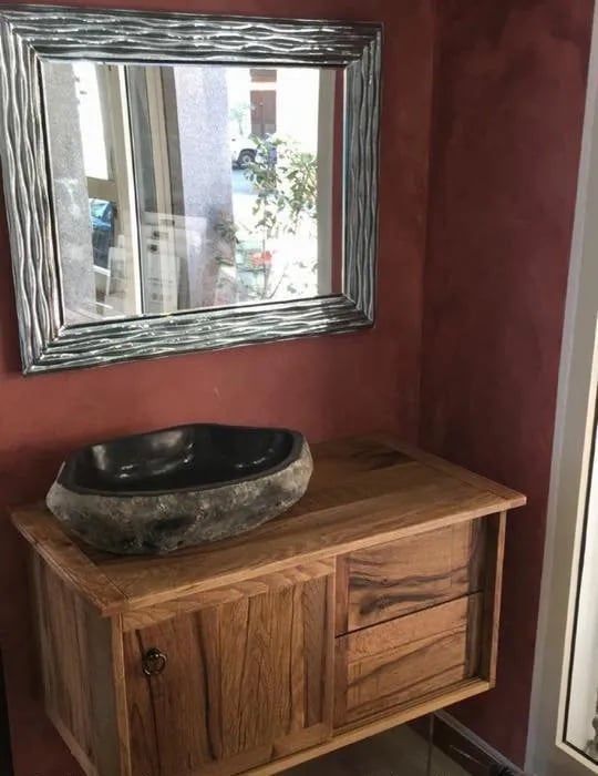 Un bagno con mobiletto in legno, lavandino e specchio.