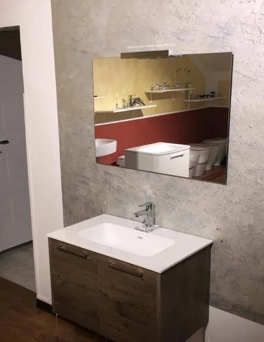 Un bagno con un lavandino e uno specchio sul muro