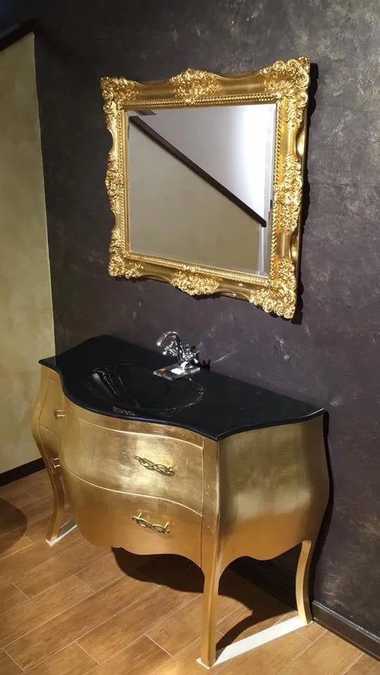 Un bagno con cassettiera dorata, lavandino e specchio.