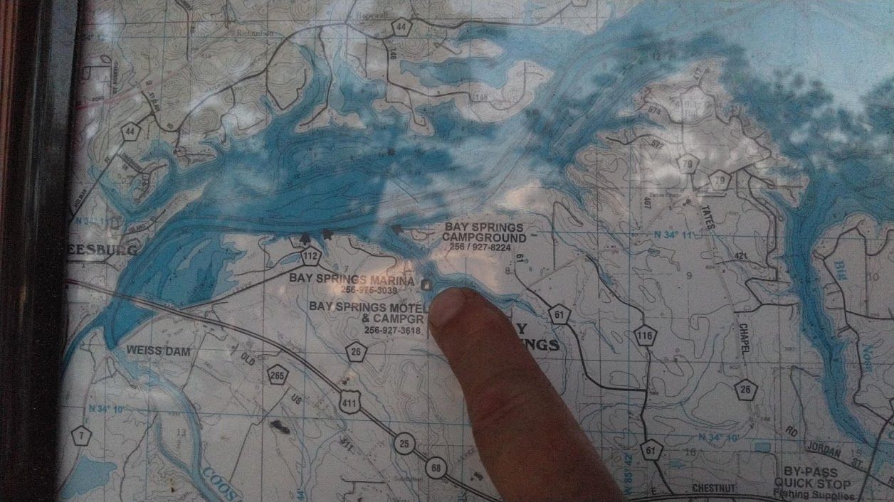 A close-up of a person pointing to a specific location on a map of a river or waterway system.