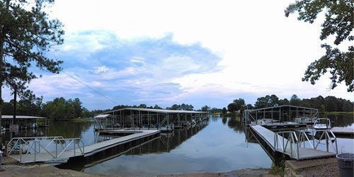 Floating docks and boat slips extending into a calm lake under a cloudy sky.