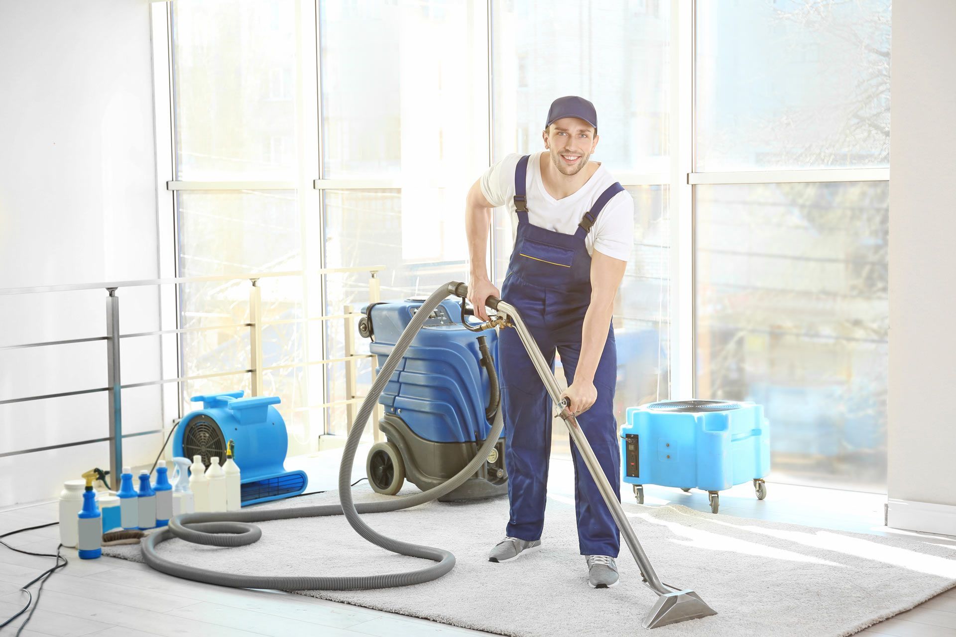 A man is cleaning a carpet with a vacuum cleaner.