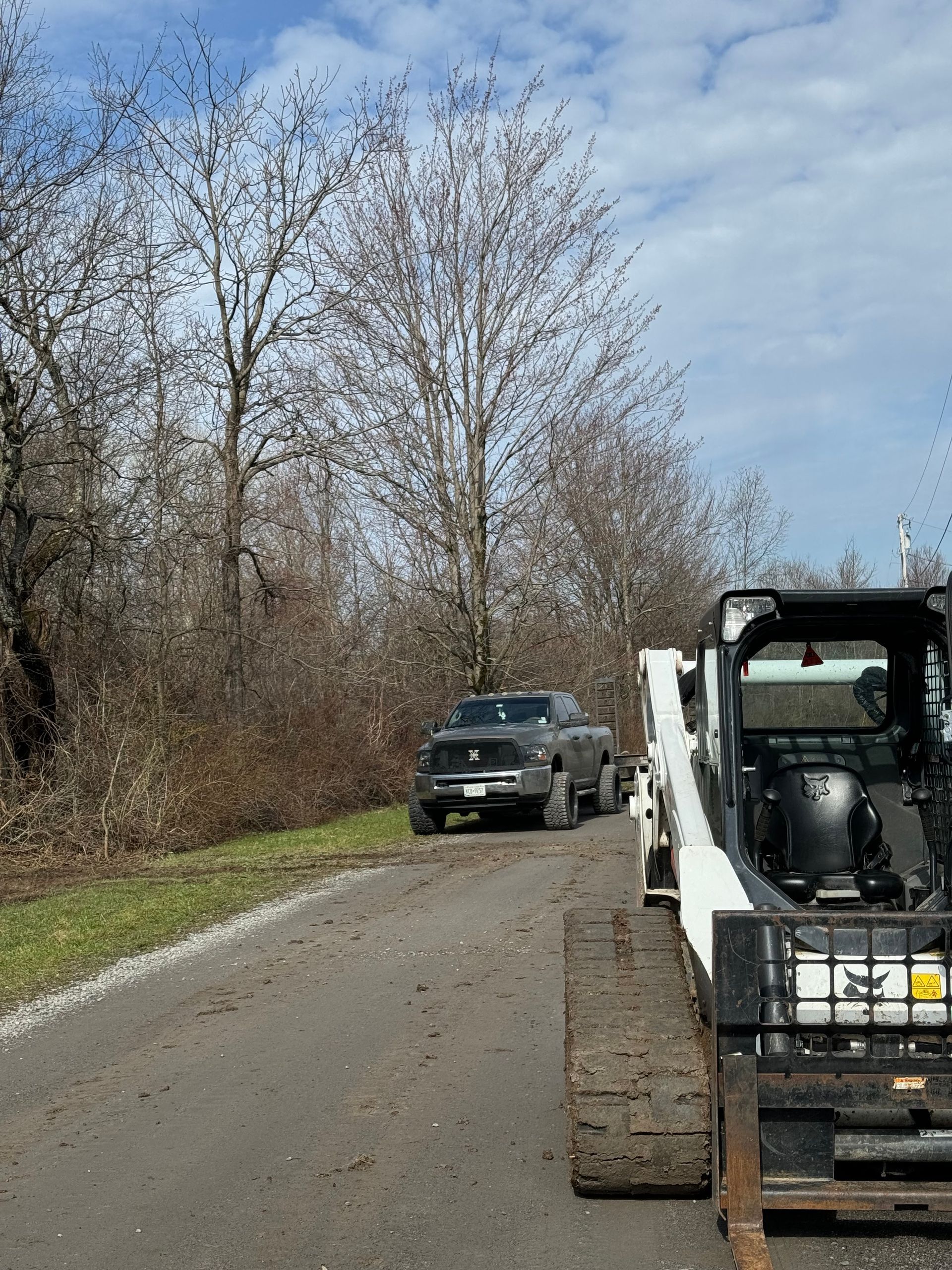 A bulldozer is driving down a road next to a truck.