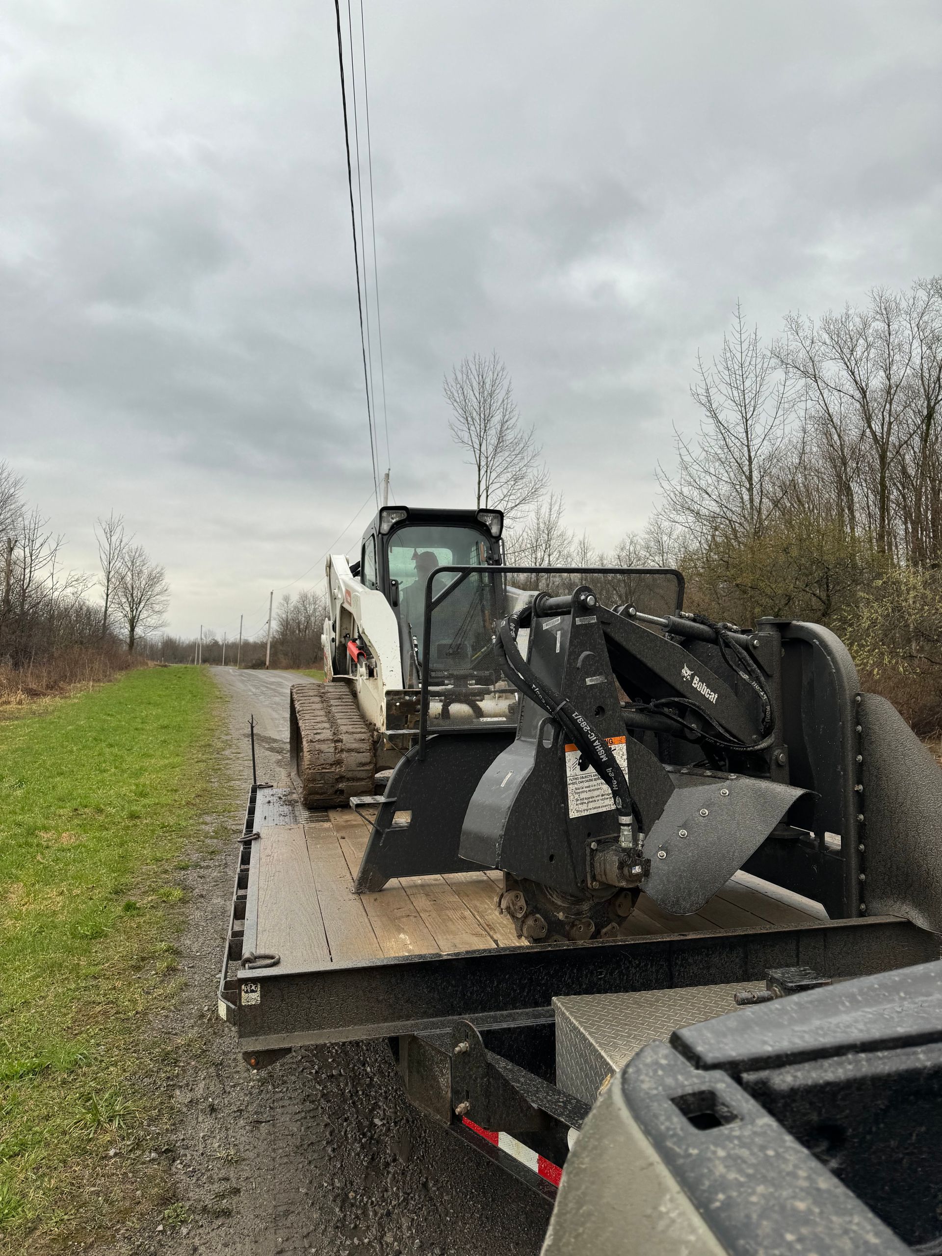 A bulldozer is sitting on top of a trailer next to a truck.