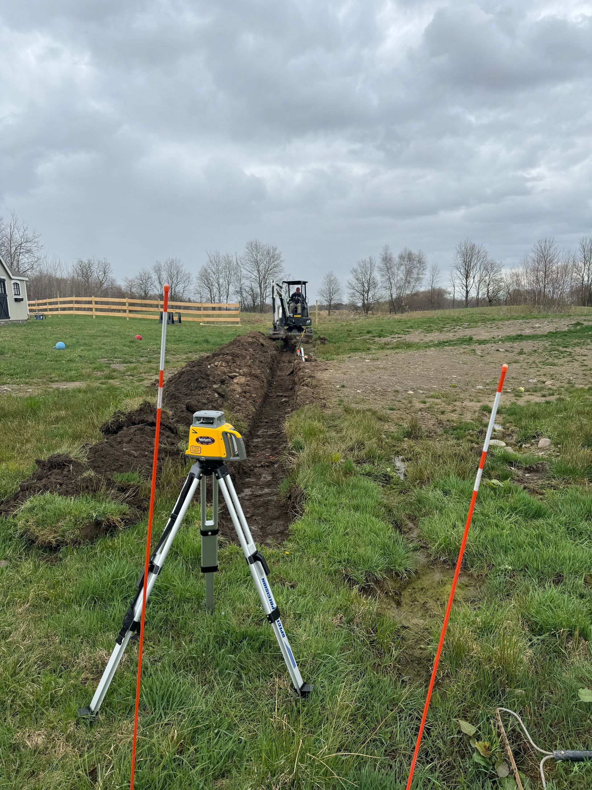 A laser level is sitting on top of a tripod in a field.