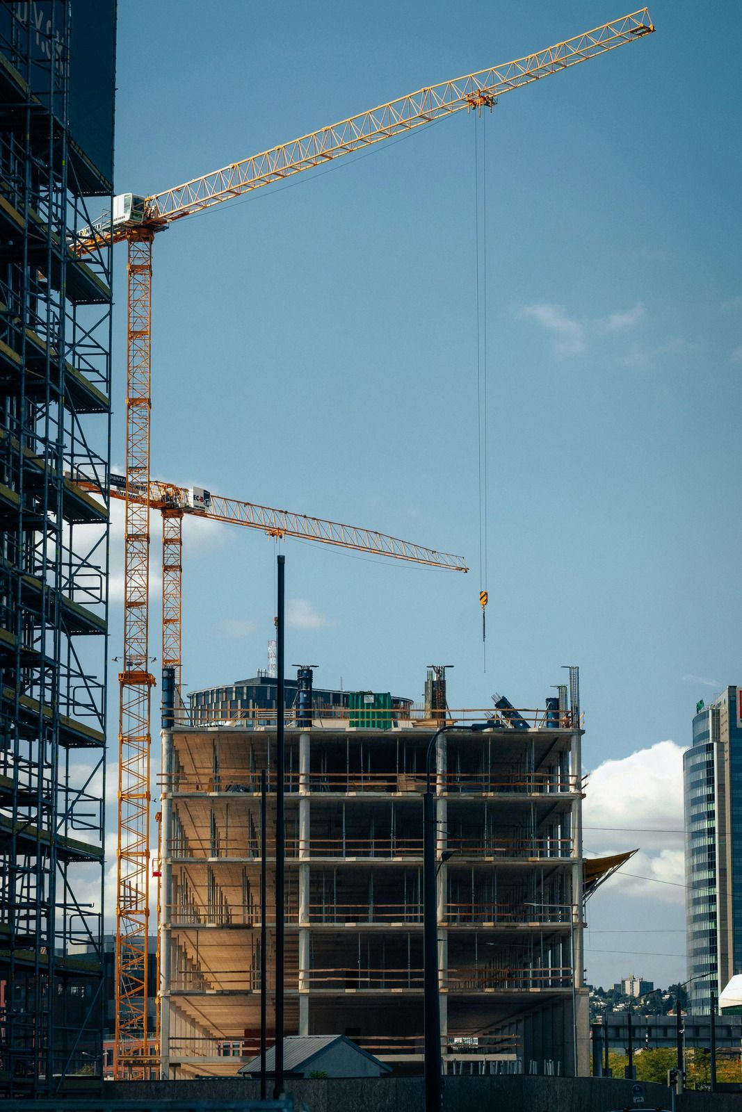 Construction site with two cranes, unfinished building frames, and blue sky.