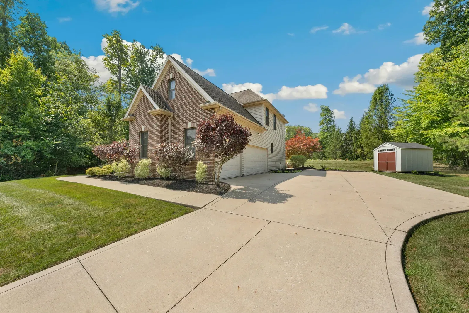 A house with a large driveway and a shed in the backyard.