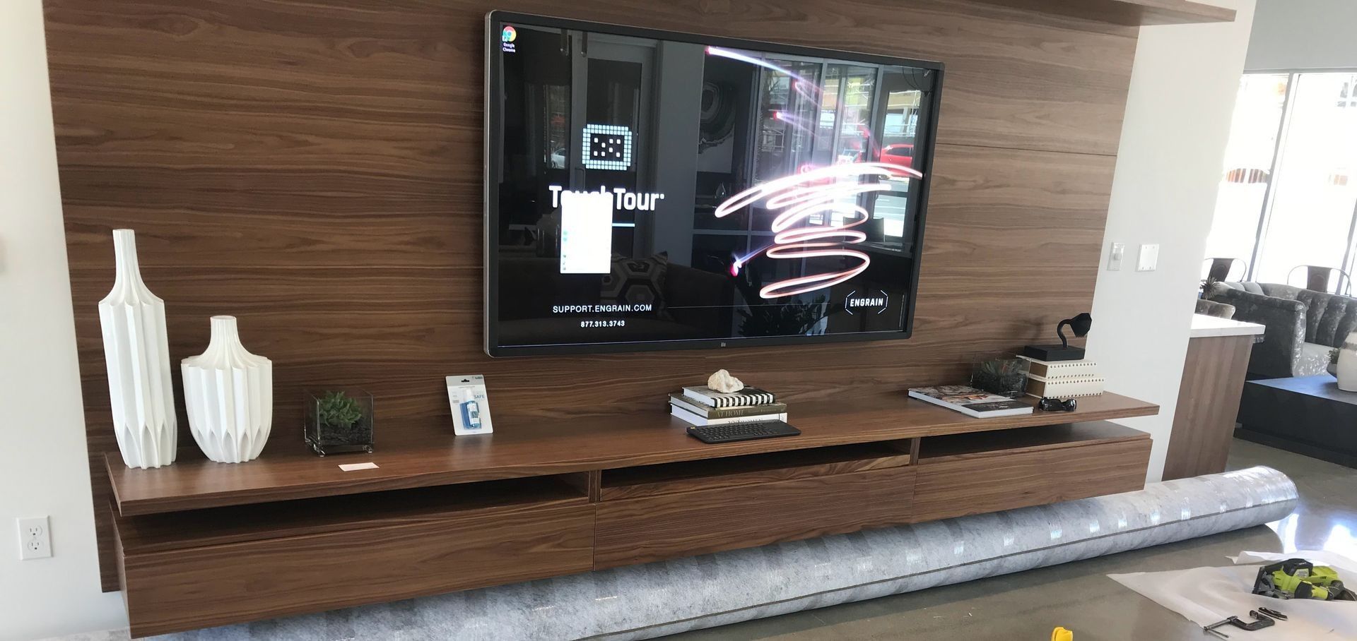 A living room with a wooden entertainment center and a flat screen tv on the wall.