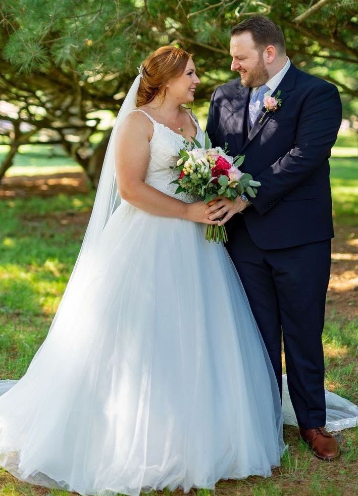 A bride and groom are posing for a picture in a park.