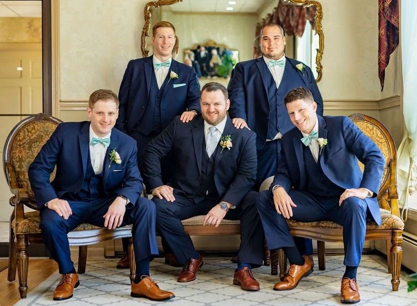 A group of men in suits and bow ties are posing for a picture.