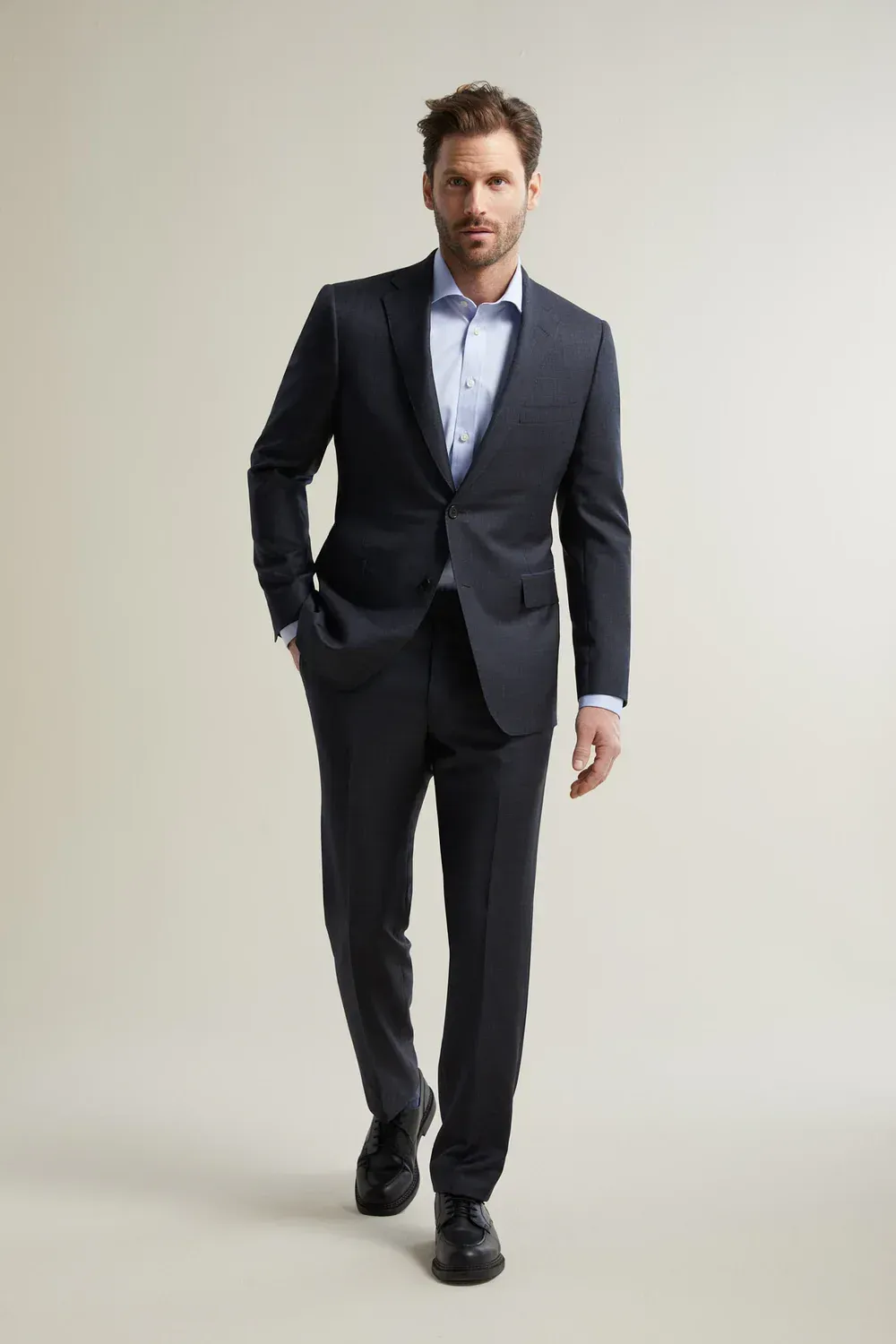 A man in a suit is walking with his hands in his pockets.