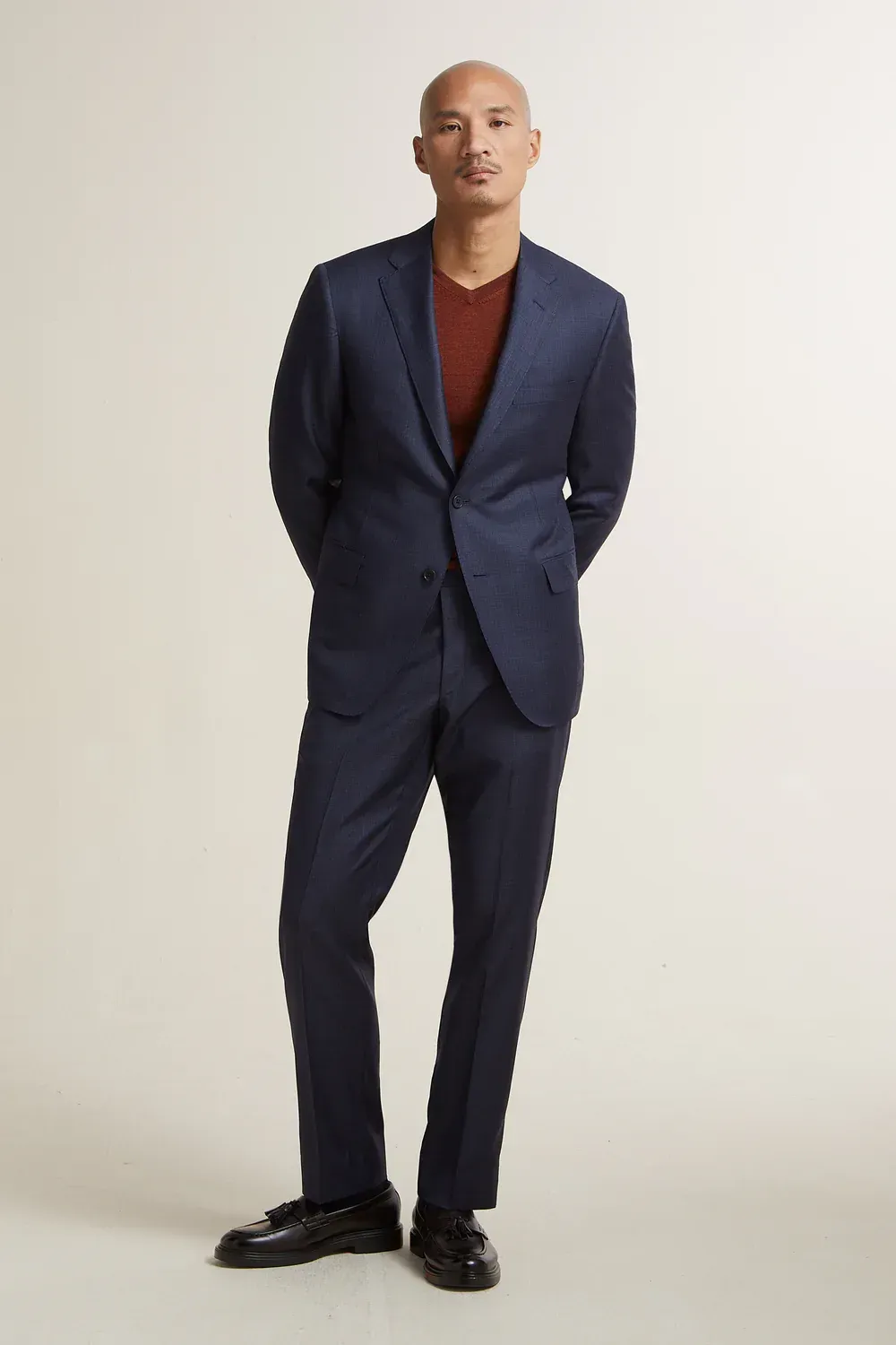 A bald man is wearing a blue suit and a red shirt.