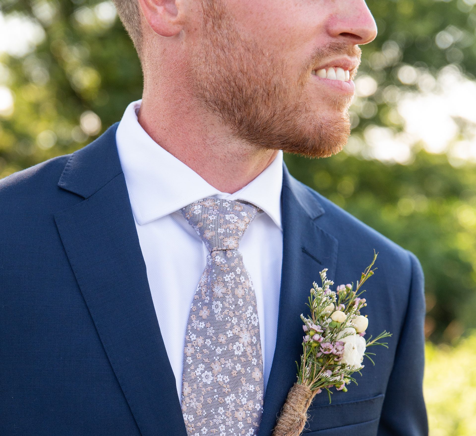 A man in a suit and tie has a flower in his pocket