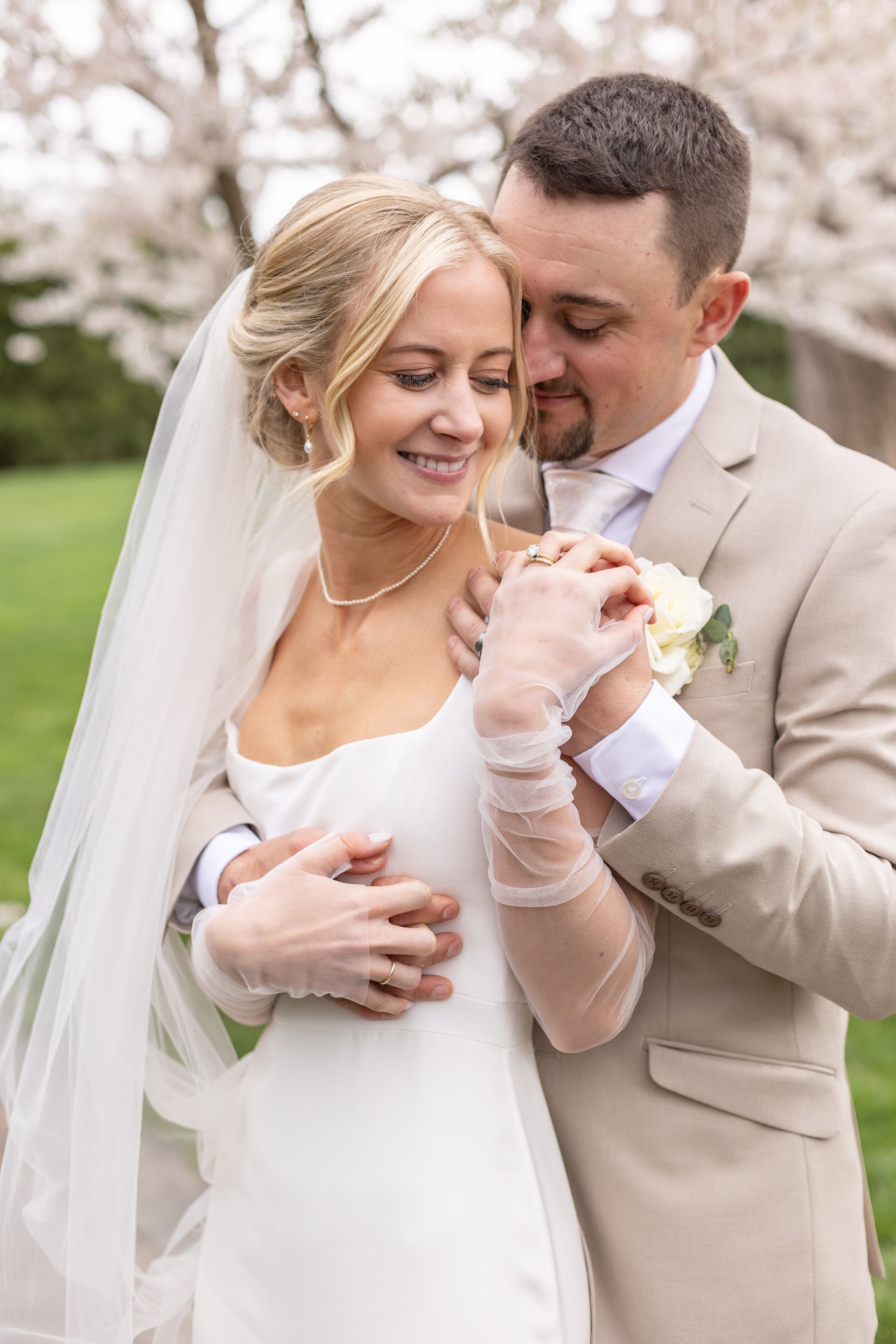 A bride and groom are posing for a picture in front of a cherry blossom tree.