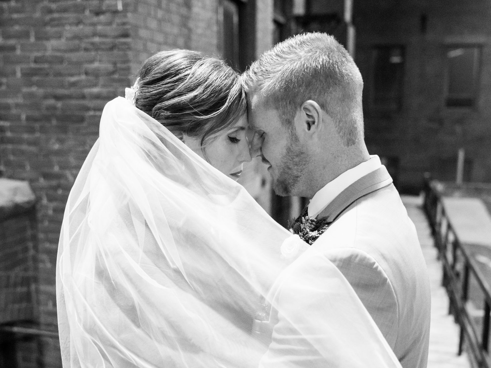A bride and groom are kissing in a black and white photo.