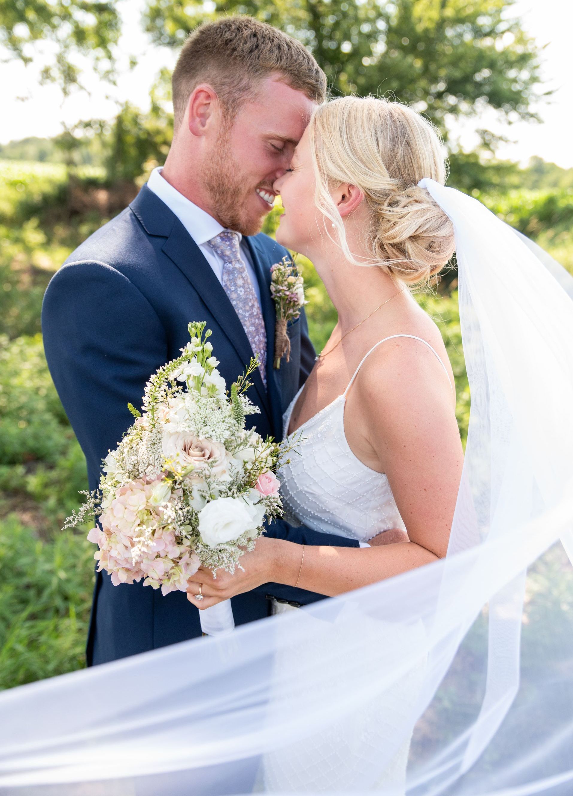 A bride and groom are standing in front of a white curtain.