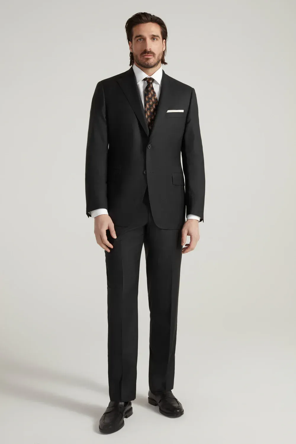 A man is wearing a black suit and tie.