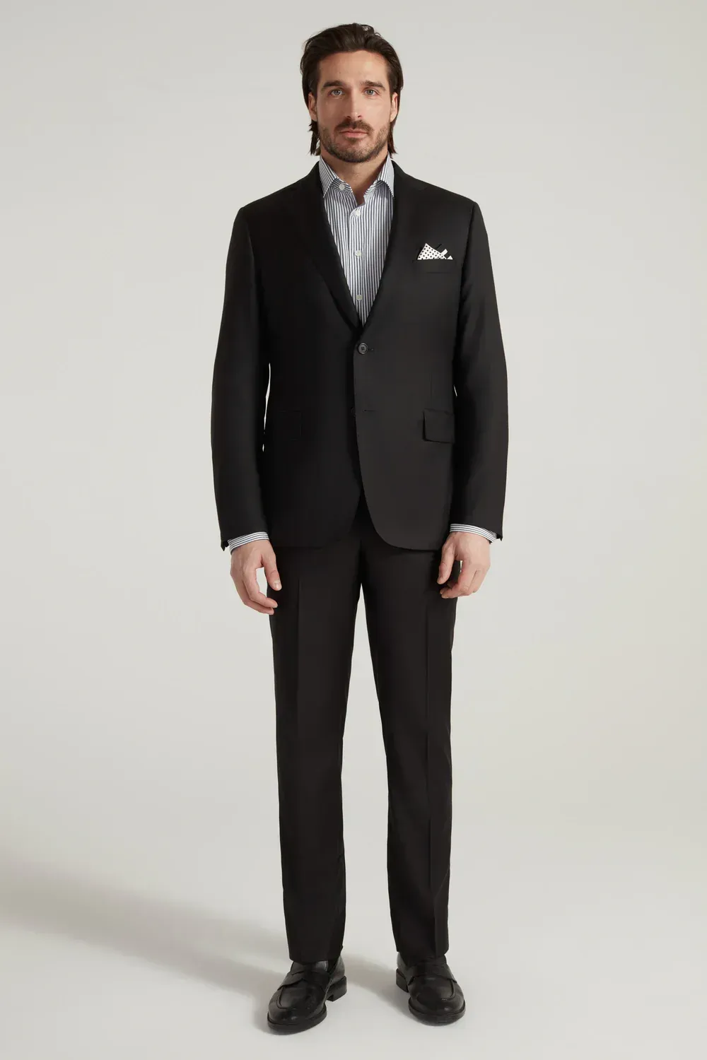 A man is wearing a black suit and a white shirt.