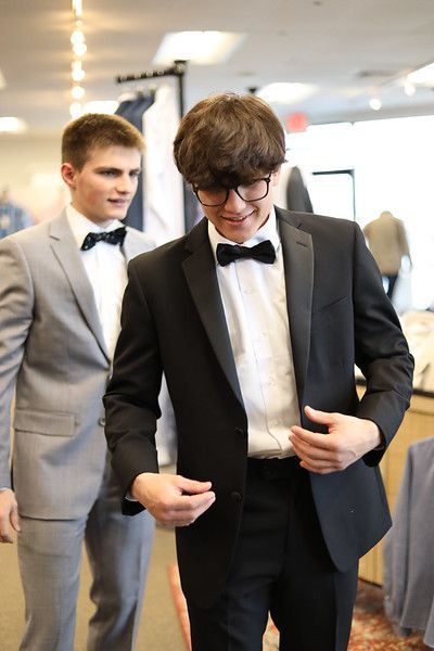 A man in a tuxedo is standing next to another man in a suit