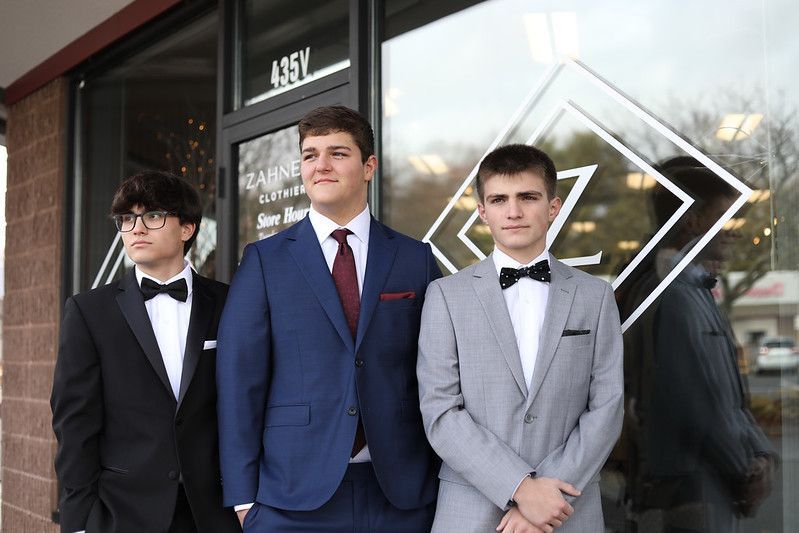 Three men in suits and bow ties are standing in front of a building.