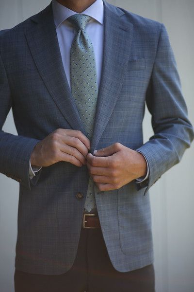 A man in a suit and tie is adjusting his jacket