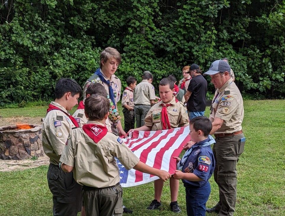 A group of Boy Scouts are holding an American flag