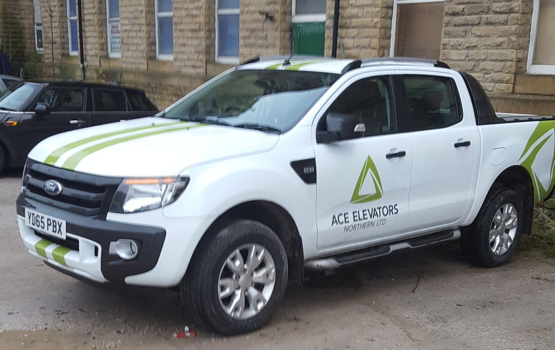 White Ford Ranger pickup truck with green stripes and company logo parked outside a building.