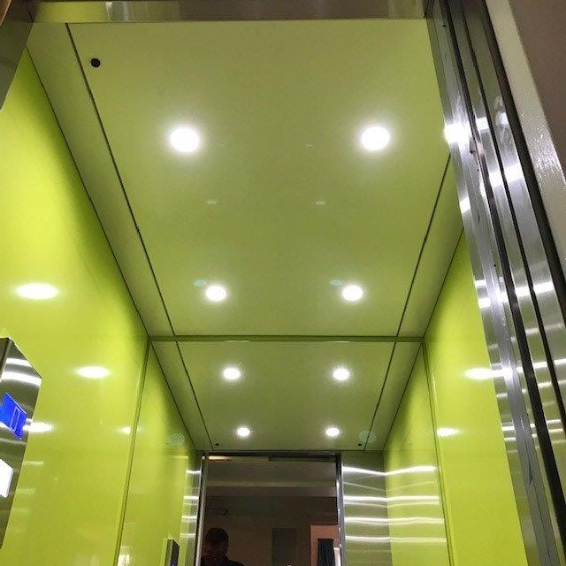 Bright yellow elevator interior with recessed lights and stainless steel accents.