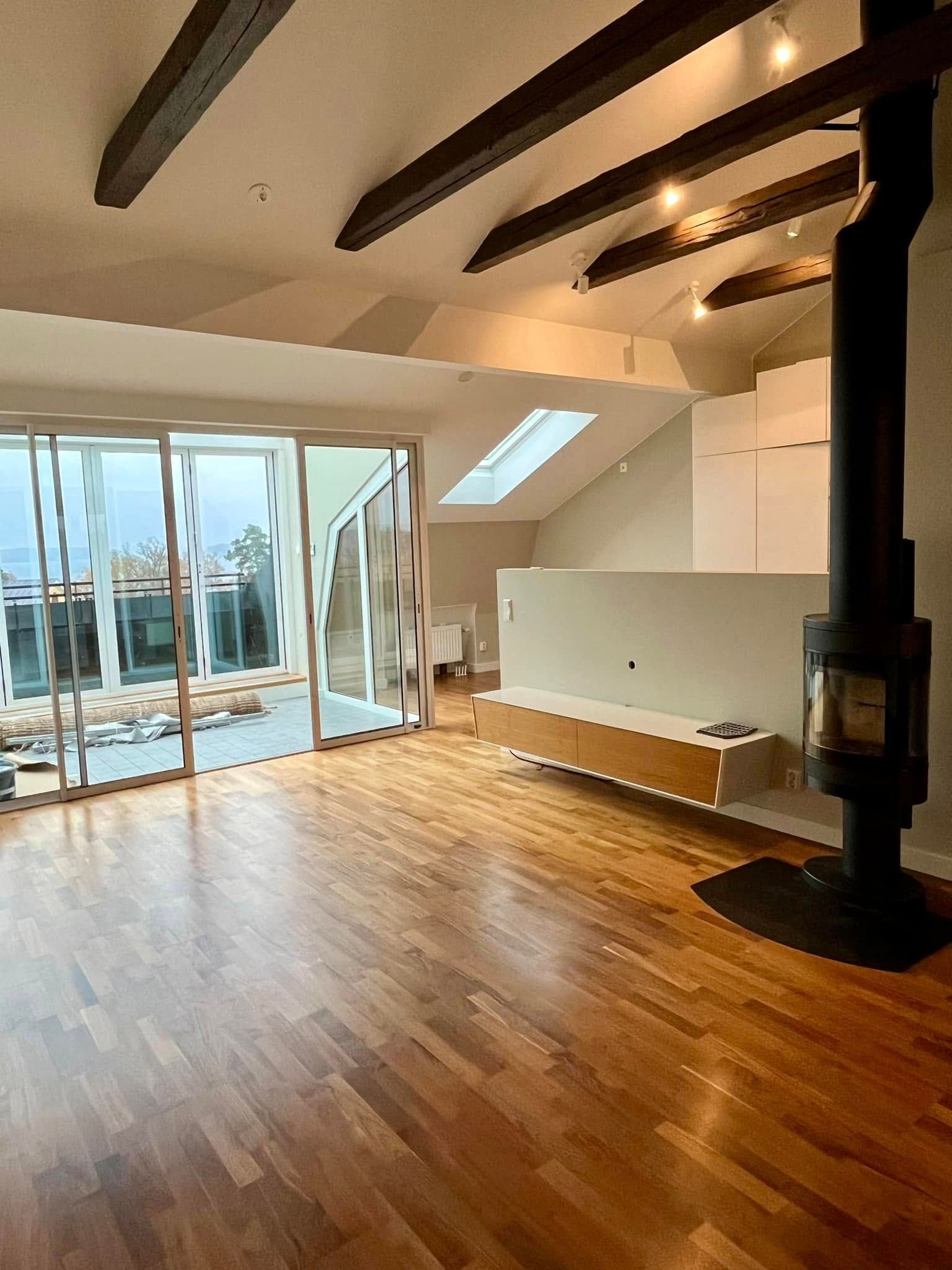 An empty living room with hardwood floors and a fireplace