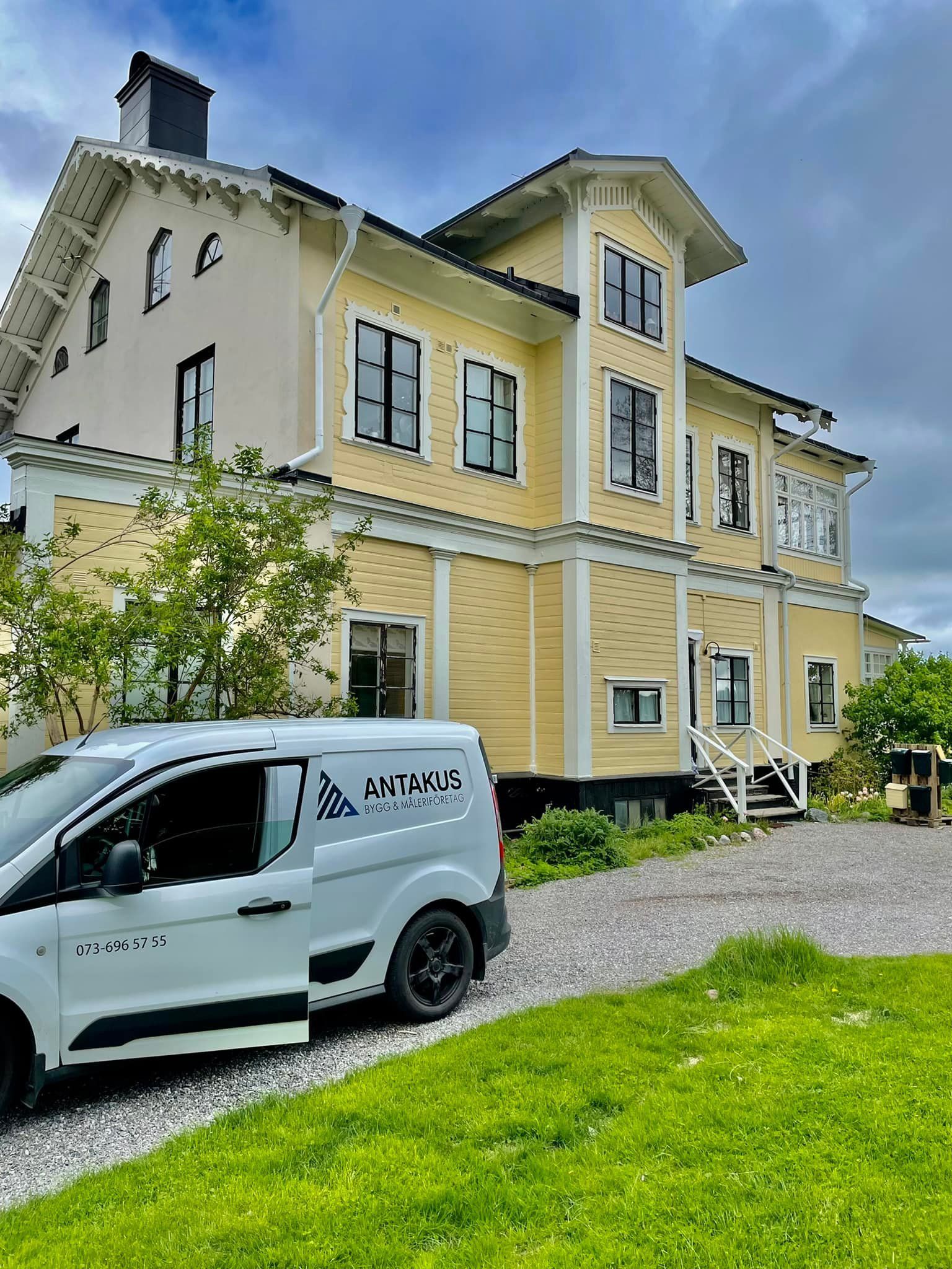A white van is parked in front of a large house.