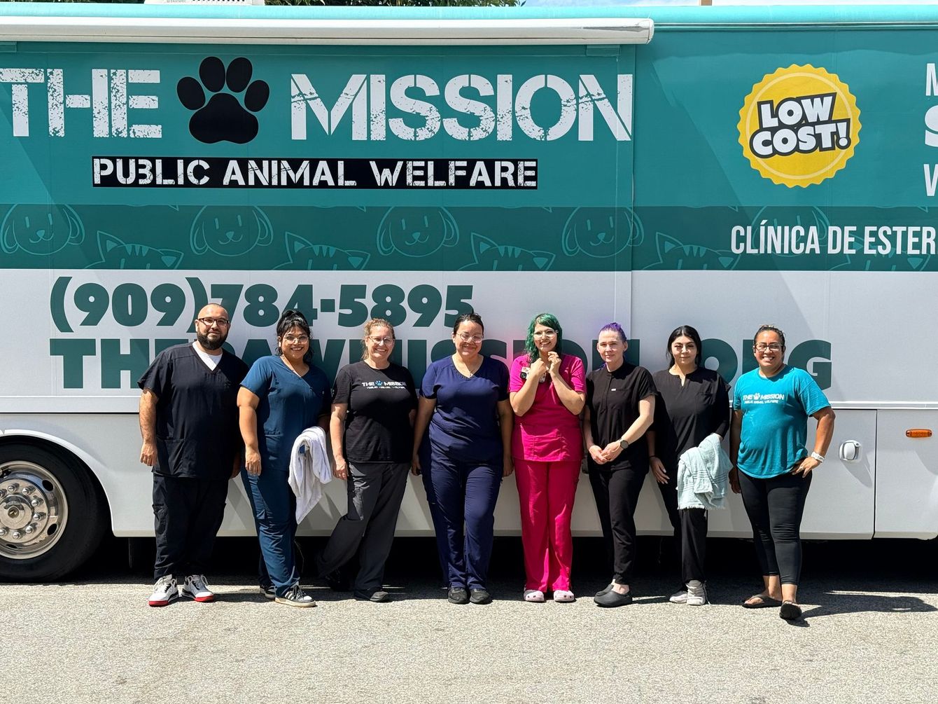 Seven people standing in front of a teal mobile animal welfare clinic bus