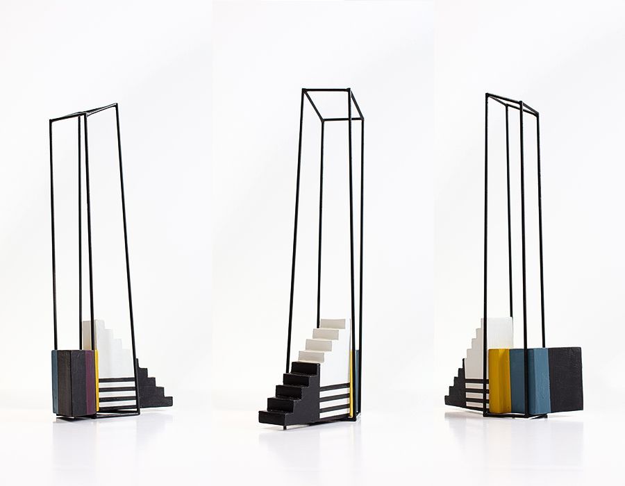 Drie geometrische sculpturen met zwarte frames en kleurrijke blokken en trappen.