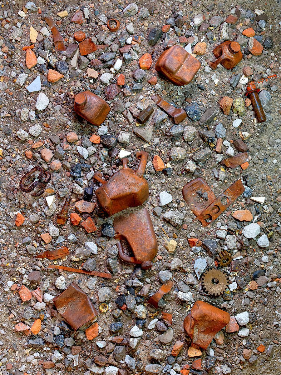 De grond was bedekt met grind, gebroken bakstenen en verspreide roestige plastic kannen en machineonderdelen.