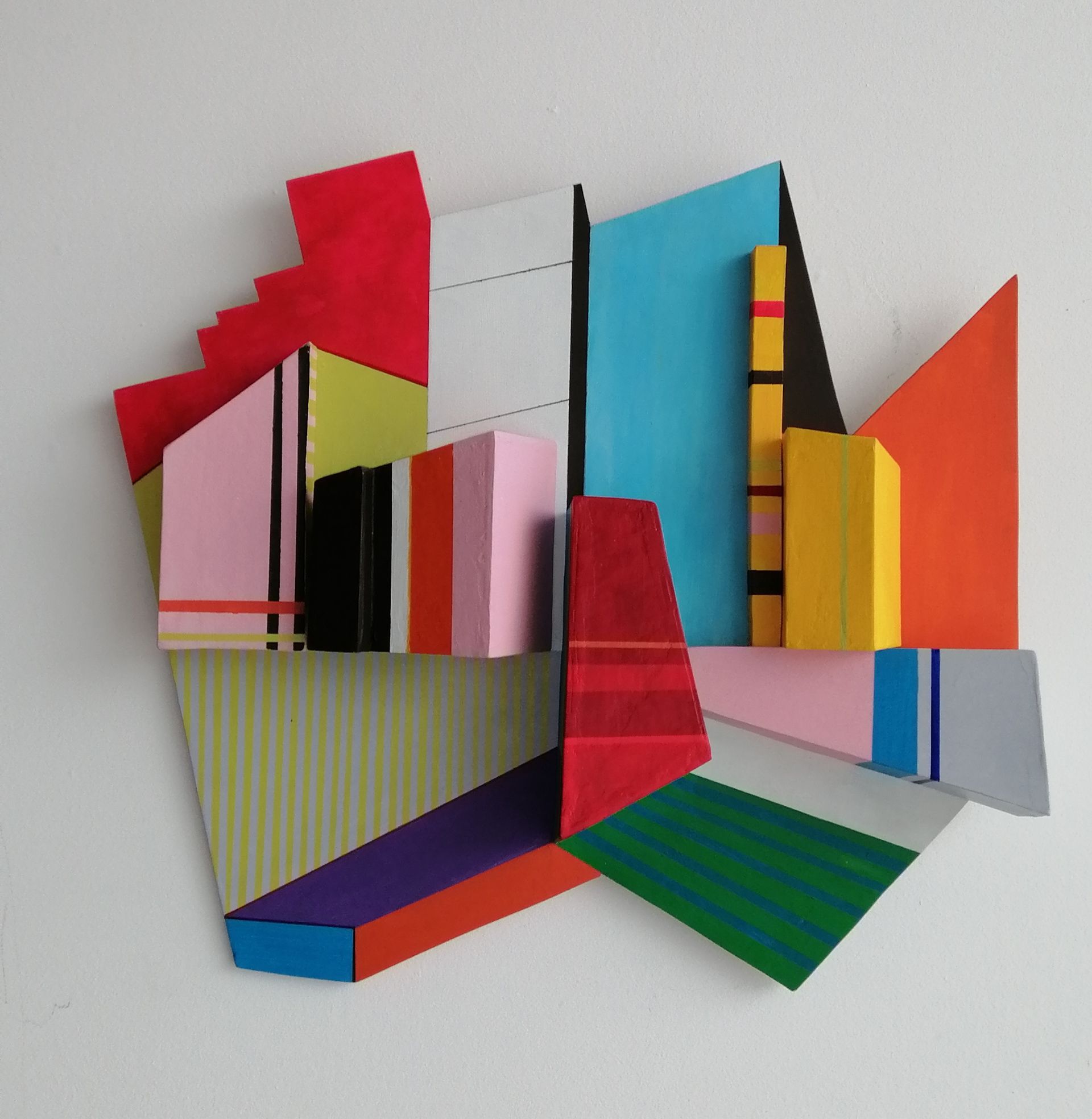 Abstracte, geometrische wandsculptuur met kleurrijk beschilderde houten blokken.