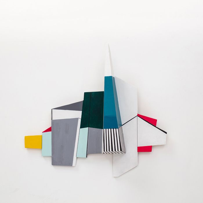 Abstracte geometrische sculptuur met kleurrijk beschilderde houten vormen tegen een witte achtergrond.