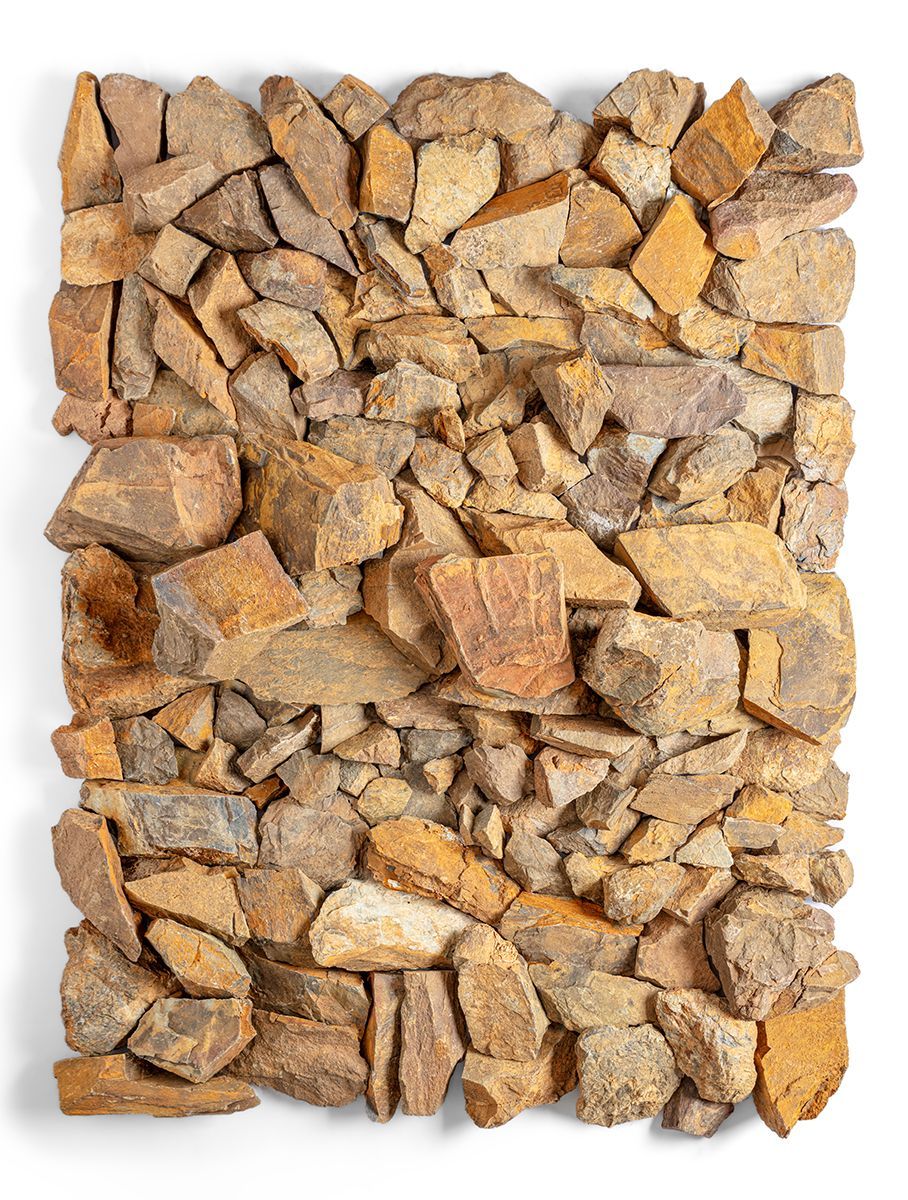 Een ruwe, rechthoekige muur, opgetrokken uit onregelmatig gevormde, bruine en beige stenen.