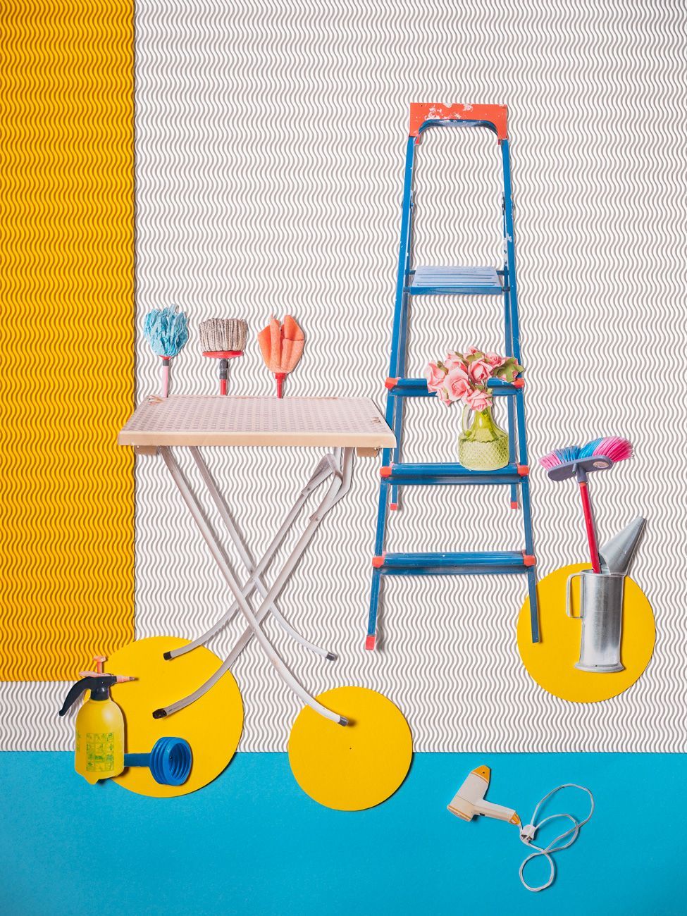 Een ladder, een tafel met kwasten, bloemen, schoonmaakspullen en een spuitfles op een lichte achtergrond.