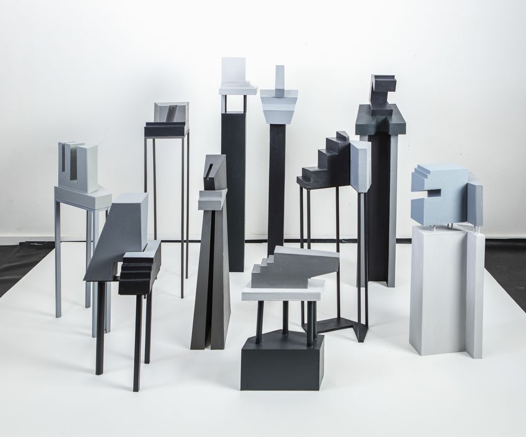 Een groep abstracte sculpturen in grijs en zwart op een witte achtergrond.