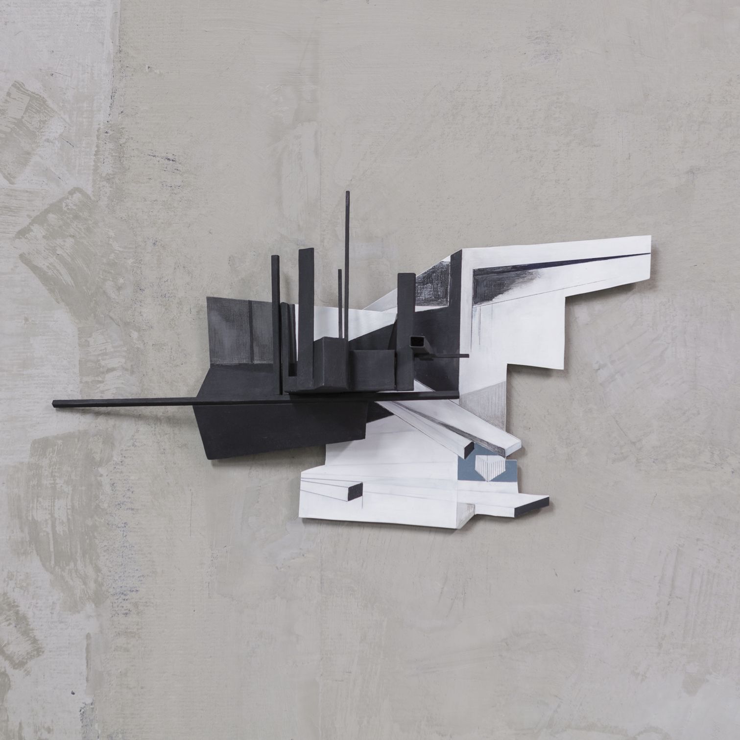 Abstracte sculptuur op een grijze muur; zwart-witte geometrische vormen en spitsen.