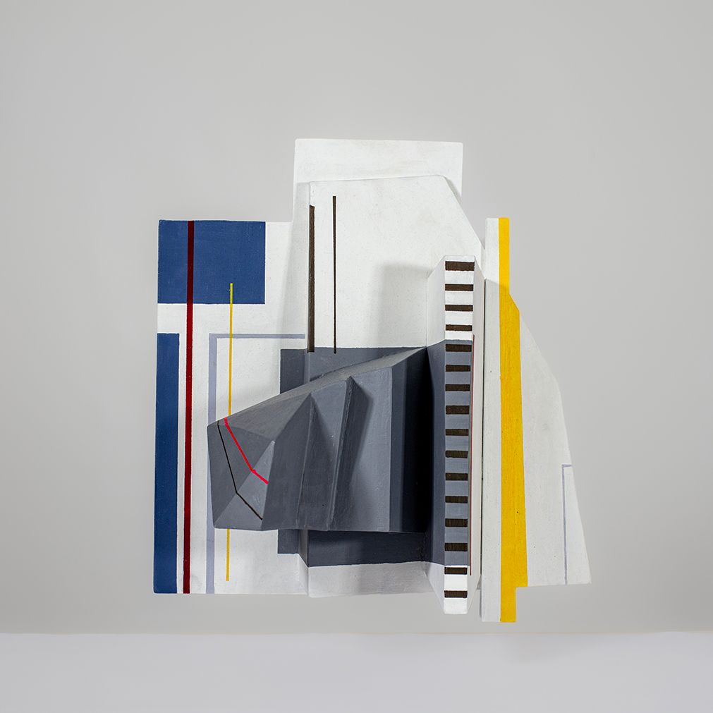 Geometrische sculptuur met blauwe, witte, grijze en gele vormen, met lijnen en rechthoeken.